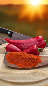 Paprika und Paprikapulver auf einem Holzbrett vor Sonnenuntergang